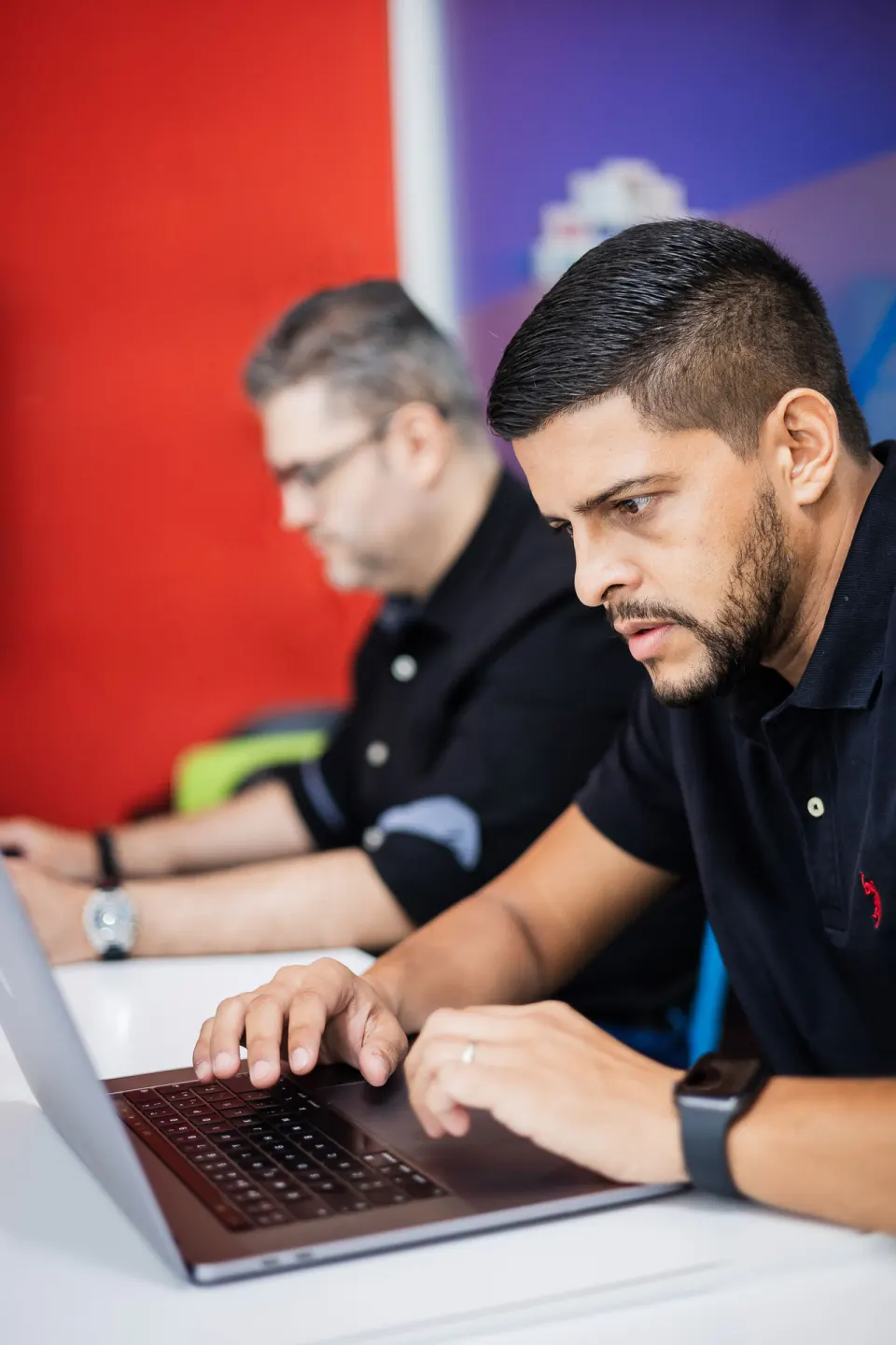 Dos integrantes de IDEACTIVO concentrados escribiendo código en sus laptops