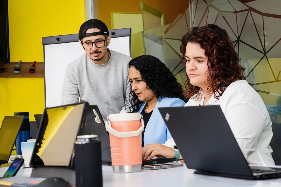 Tres integrantes del equipo de IDEACTIVO revisan juntos un proyecto en una laptop