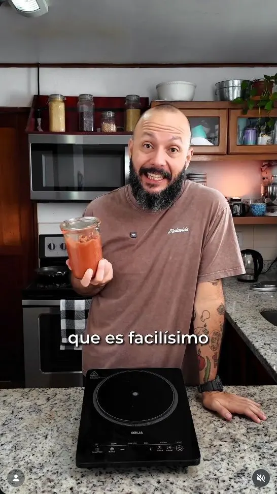 Content creator in a kitchen holding a jar of jam next to a DRIJA induction cooktop